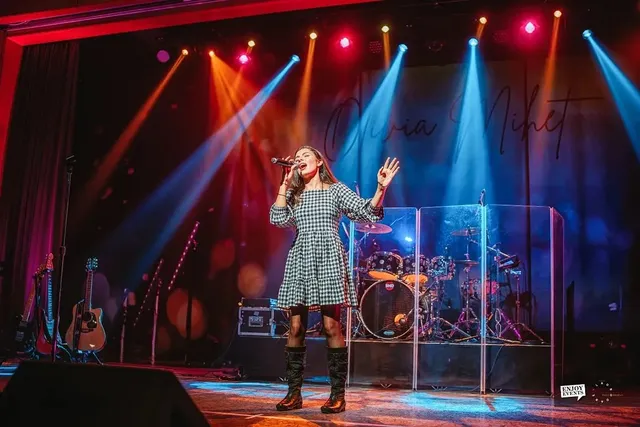 Full concert stage with band equipment, coloured stage lighting and a script signature backdrop